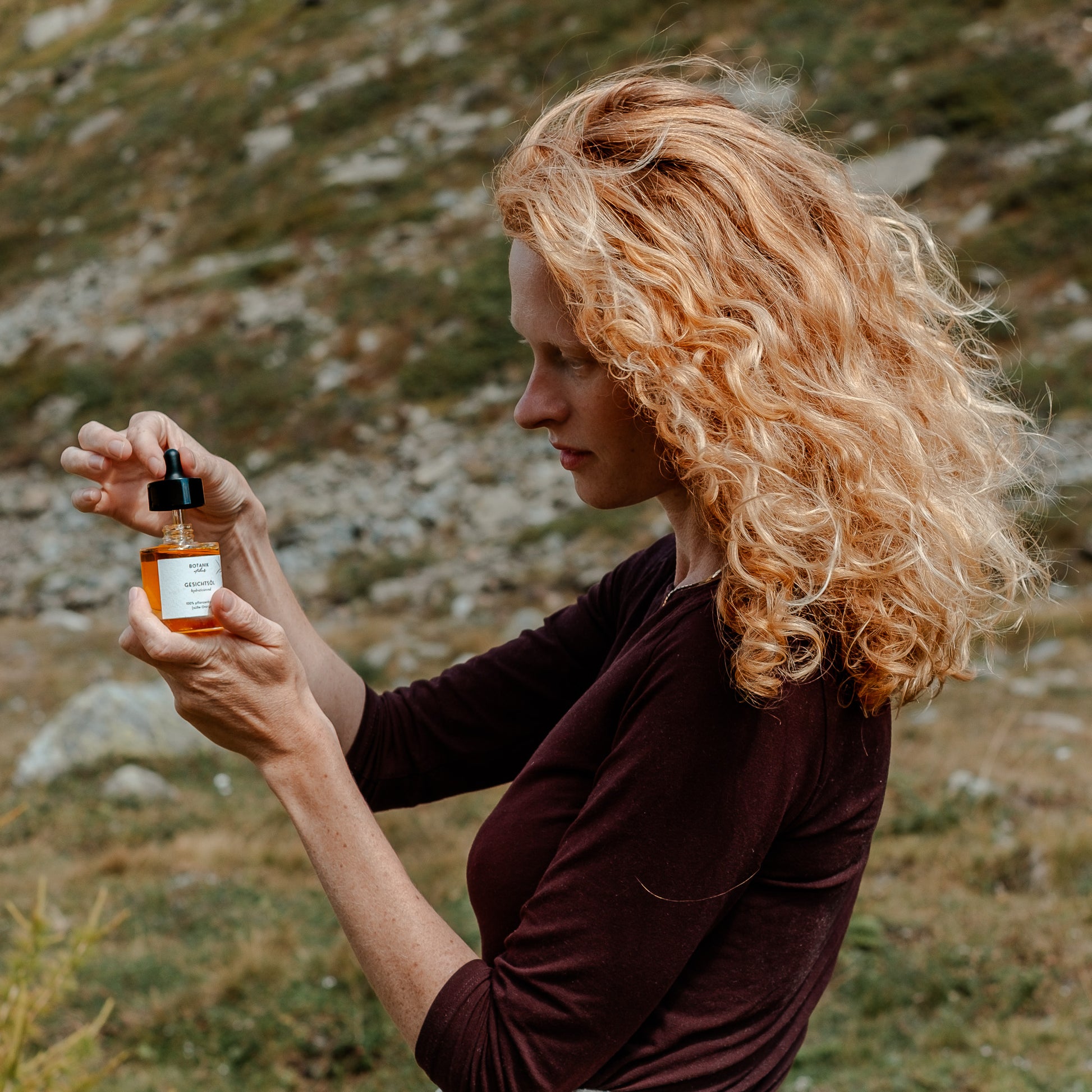 Frau mit roten Locken öffnet das hydratisierende Gesichtsöl von Botanik Atelier.