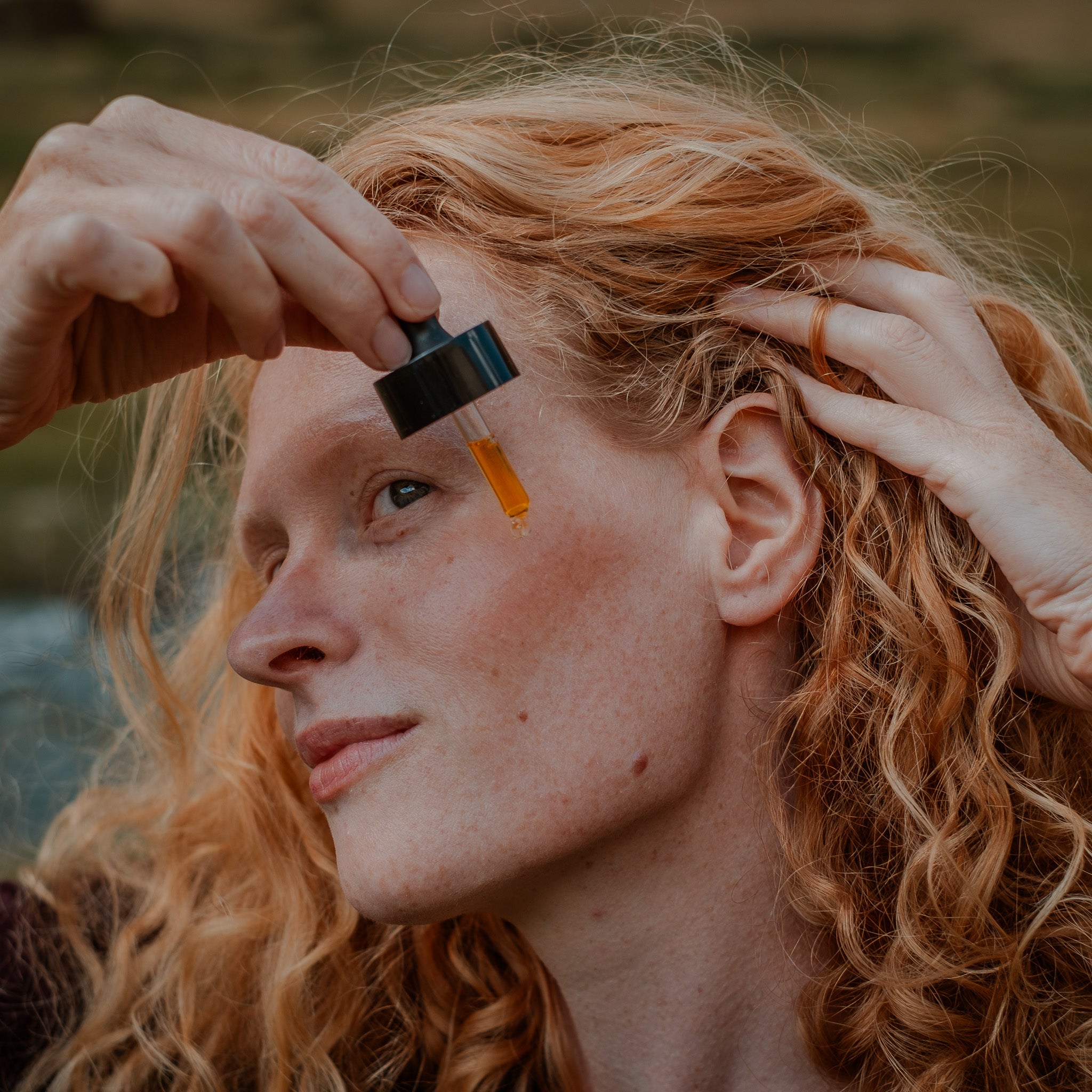 Frau mit roten Locken trägt das hydratisierende Gesichtsöl von Botanik Atelier auf die Wange auf.