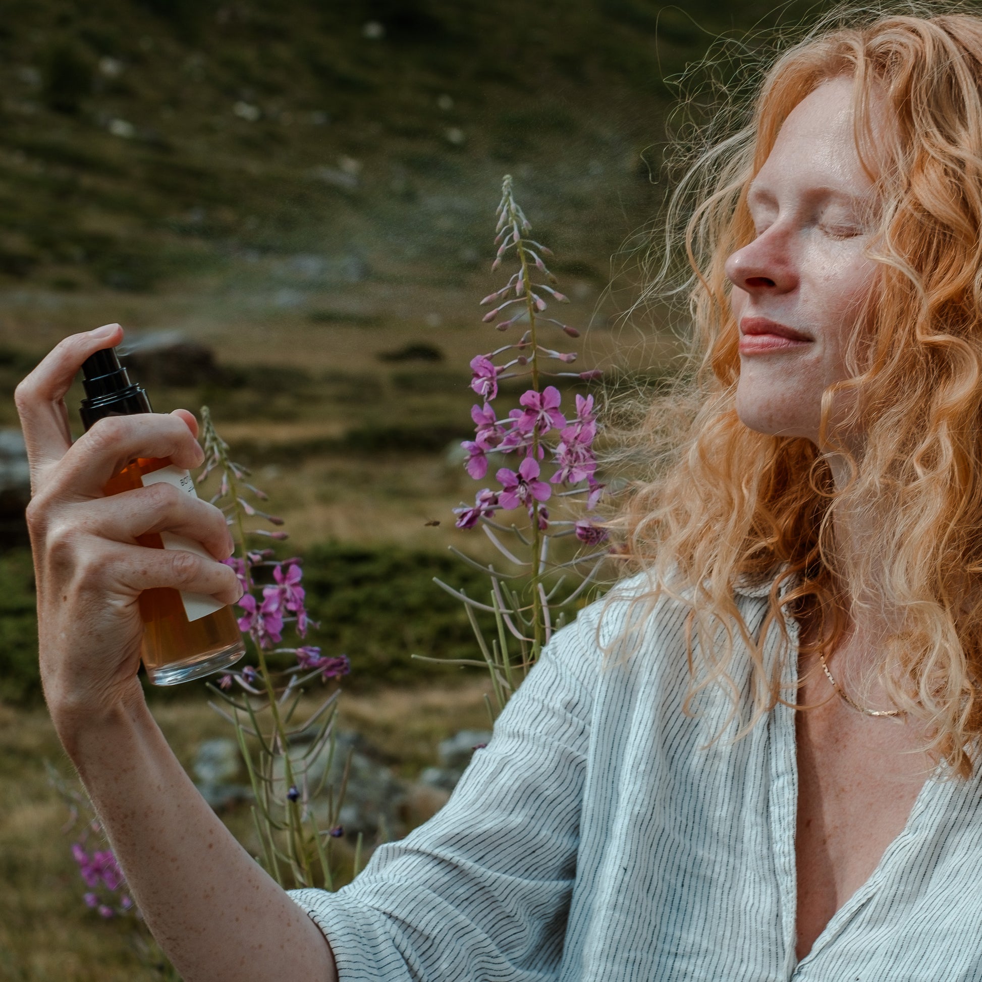 Frau mit roten Locken sprüht das Blüten Tonikum mit 5% Niacinamide von Botanik Atelier, ein natürliches Gesichtswasser, auf die Gesichtshaut.